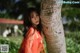 A woman leaning against a palm tree in a park.