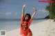 A woman in a red dress standing on a beach.