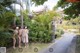 A group of naked women walking down a path in a garden.