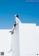 A woman sitting on top of a white wall.