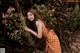 A woman in a polka dot dress leaning against a tree.