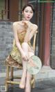 A woman sitting on a chair holding a fan.