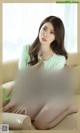 A woman in a green shirt is sitting on a couch.