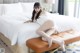 A woman sitting on top of a bed in a white dress.