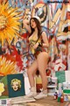 A woman standing in front of a painting on a wall.