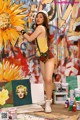 A woman standing in front of a painting of a sunflower.