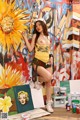 A woman posing in front of a painting of a sunflower.