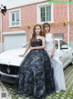 Two women standing next to a white car.