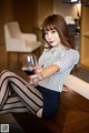 A woman sitting on a table holding a glass of wine.