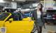 A woman standing next to a yellow sports car.