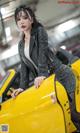 A woman leaning on the hood of a yellow sports car.