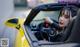 A woman sitting in the driver's seat of a yellow sports car.