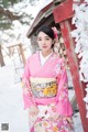 A woman in a pink kimono standing in the snow.