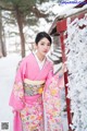 A woman in a pink kimono standing in the snow.