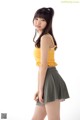 A woman in a yellow top and green skirt posing for a picture.