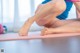 A woman sitting on a yoga mat with her feet on the floor.