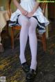 A woman sitting on a chair wearing white stockings and black shoes.