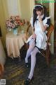 A woman in a maid outfit sitting on a chair.