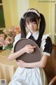 A woman in a maid outfit holding a tray.