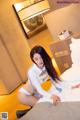 A woman in a white shirt and blue tie sitting on a bed.